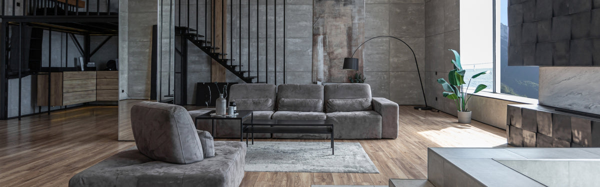 Modern gray sofa set in cozy industrial living room with wooden floors and large windows